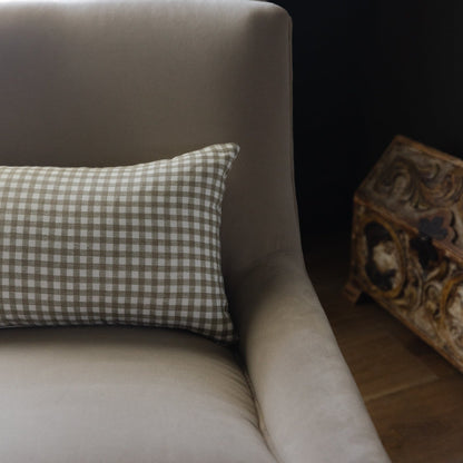Rectangular lumbar pillow with sage and white gingham pattern on upholstered chair arm.
