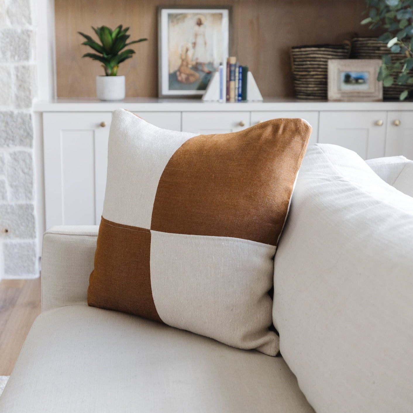 Brown and cream color-blocked square pillow on a beige sofa.