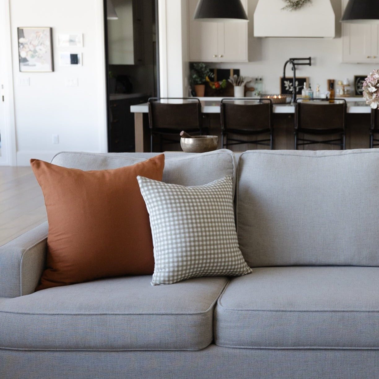 Gingham patterned pillow in sage green and white check on gray sofa.