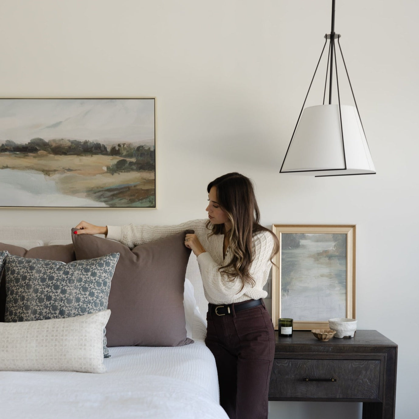Mocha-colored throw pillow displayed on bed with white and patterned pillows in bedroom setting.