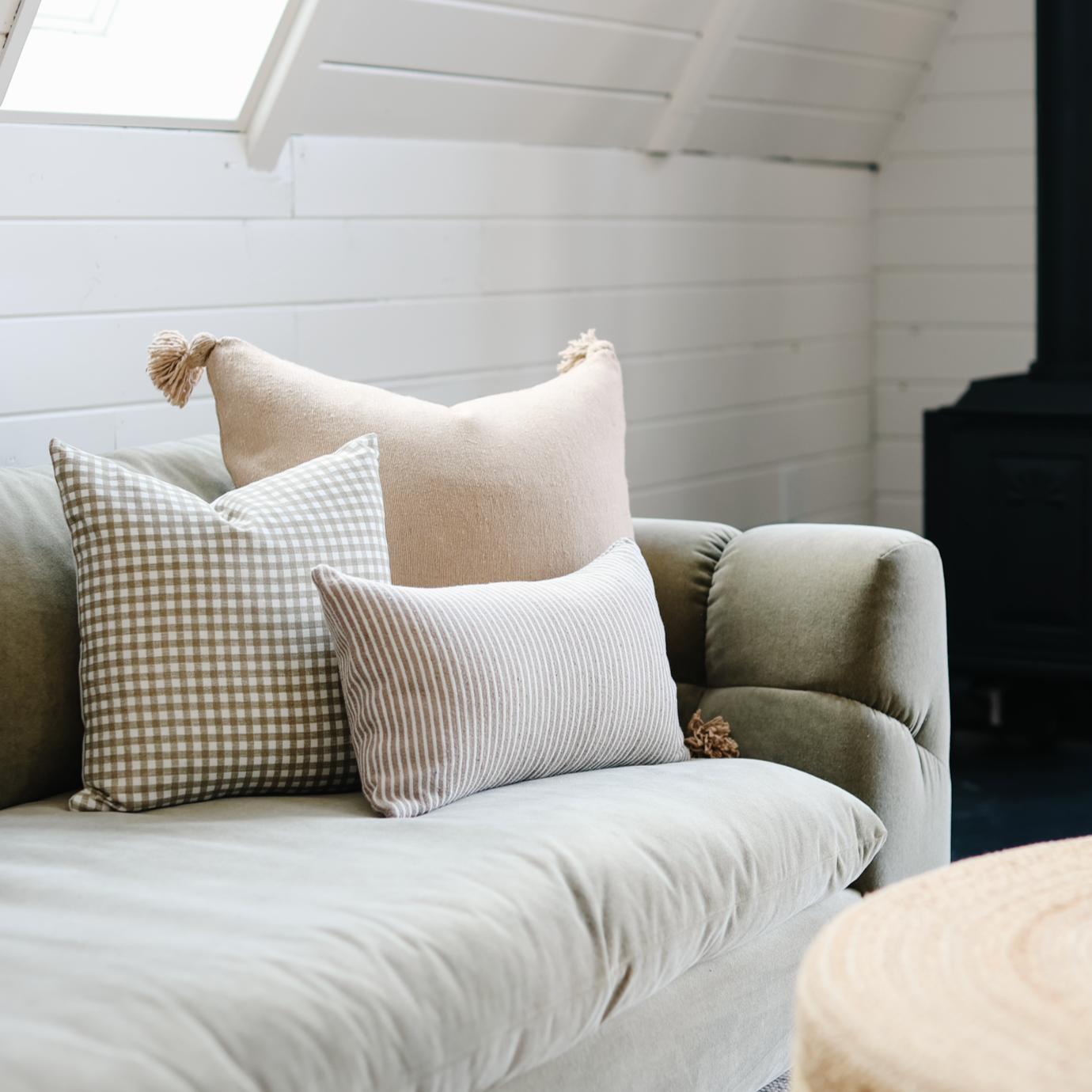 Tan and white gingham patterned pillow displayed on an upholstered chair with neutral throw pillows.
