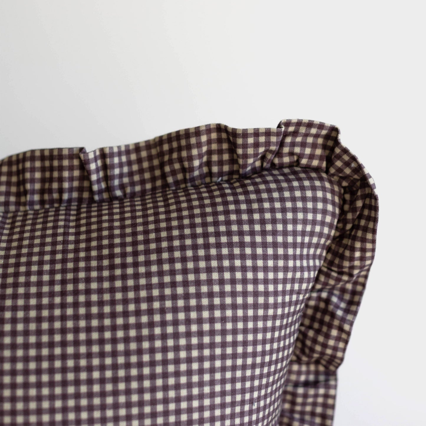 Plum and white mini gingham pillow with ruffled edges.