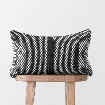 Black and white woven lumbar pillow with vertical stripe detail on wooden chair.