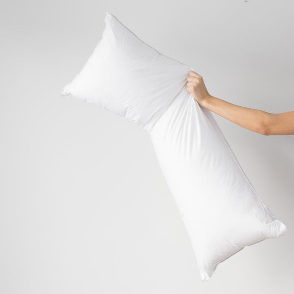 White rectangular faux down pillow insert held by hand showing its fill and soft texture.