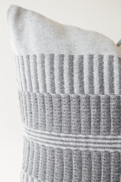 Gray and white woven pillow with vertical striped pattern and horizontal bands across center section.