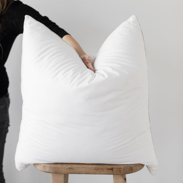 White faux down pillow insert being held open to show fill and soft texture.