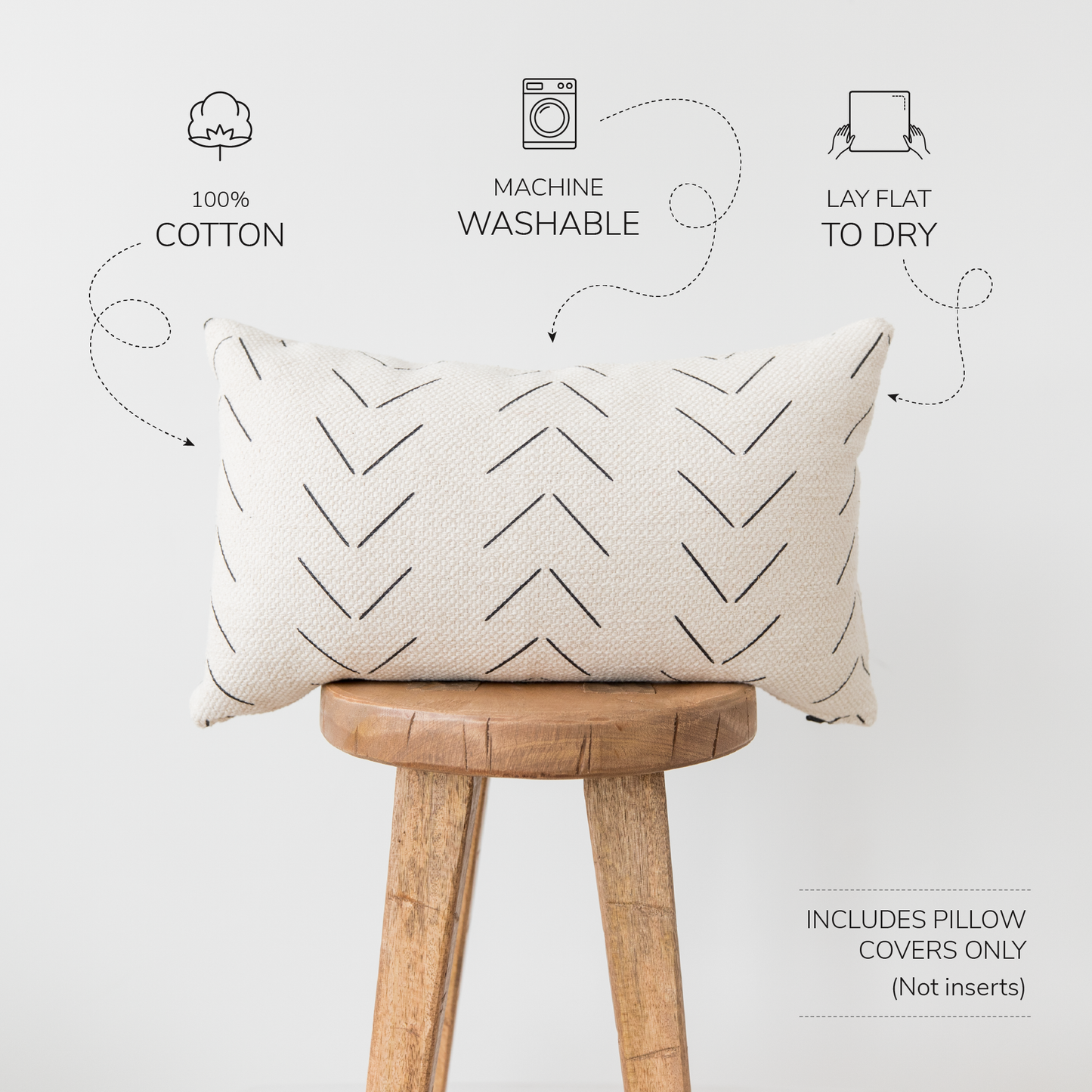 Cream lumbar pillow cover with geometric chevron pattern in charcoal, displayed on wooden stool.