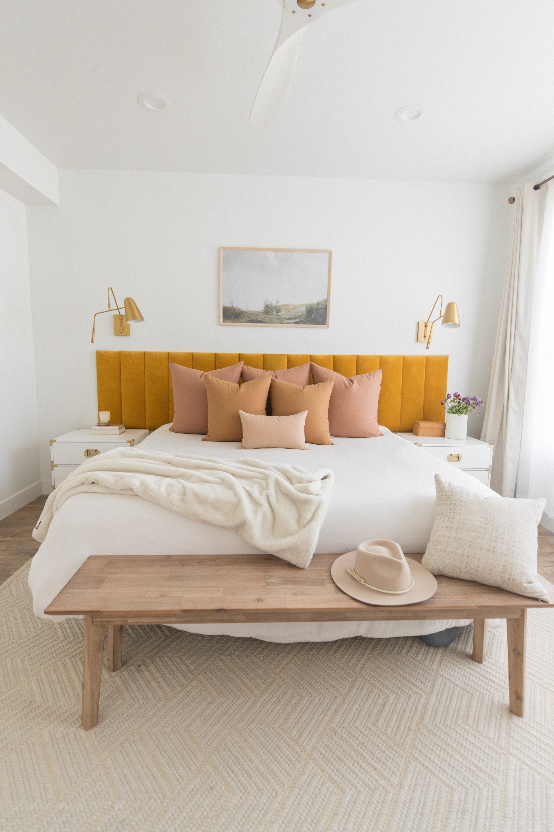 Dusty rose and tan throw pillows arranged on a bed with yellow headboard in a modern bedroom.
