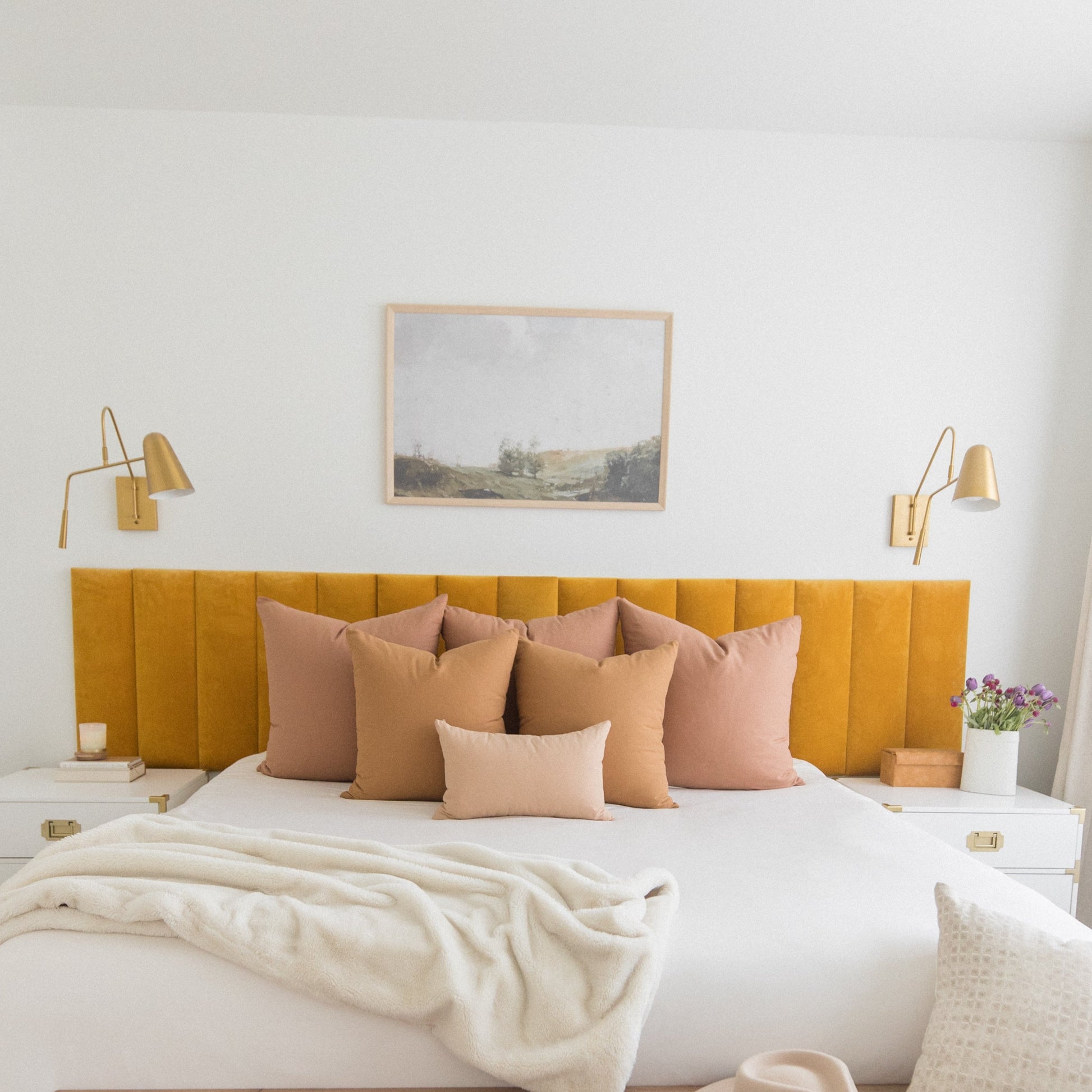 Terracotta-colored pillows arranged on a bed with mustard yellow headboard and white bedding.