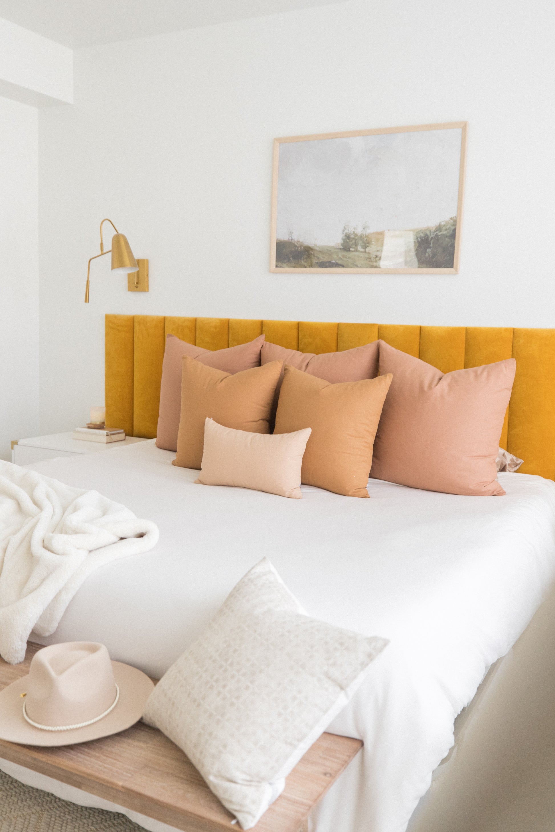 Dusty rose and peachy toned throw pillows arranged on a bed with yellow headboard.