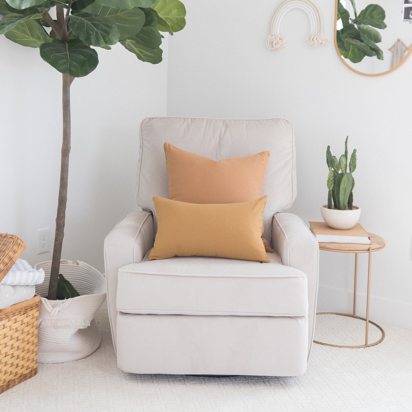 Two golden-tan rectangular pillows displayed on a cream upholstered chair in a minimalist room setting.