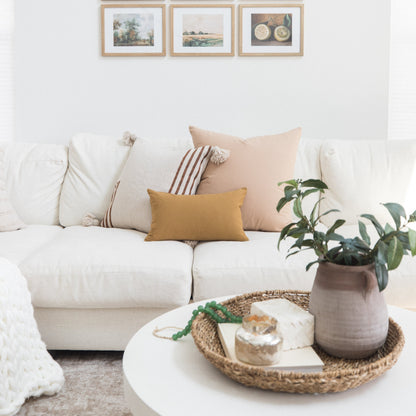 White upholstered sofa with tan and striped throw pillows in a neutral living room setting.