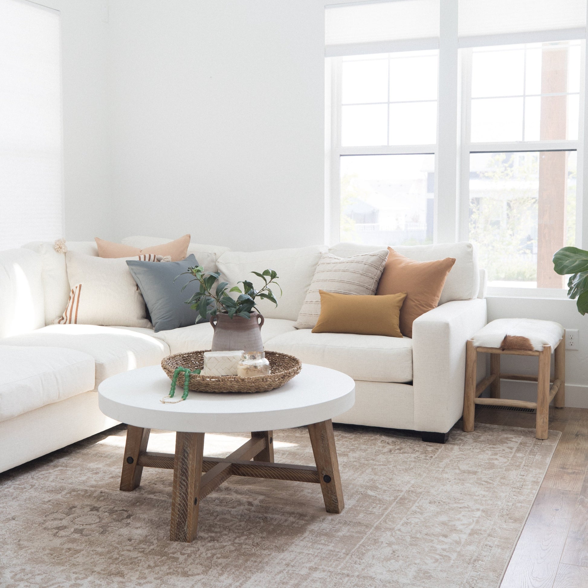 Terracotta and cream pillows arranged on a white sectional sofa in a bright living room setting.