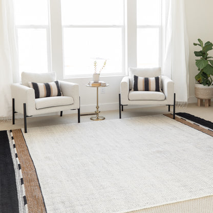 Cream armchair with black metal legs and striped accent pillow, shown in a bright living room setting.