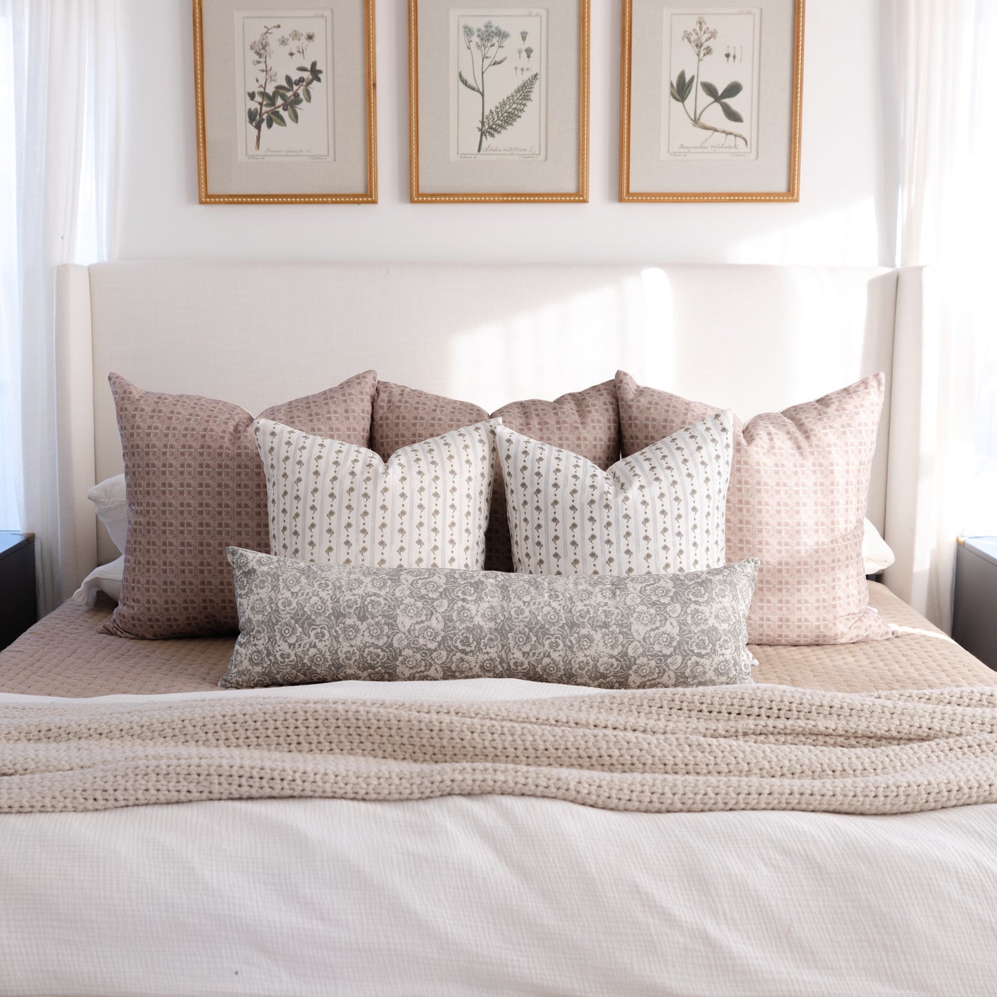 Gray and tan patterned lumbar pillow displayed on a bed with coordinating decorative pillows.