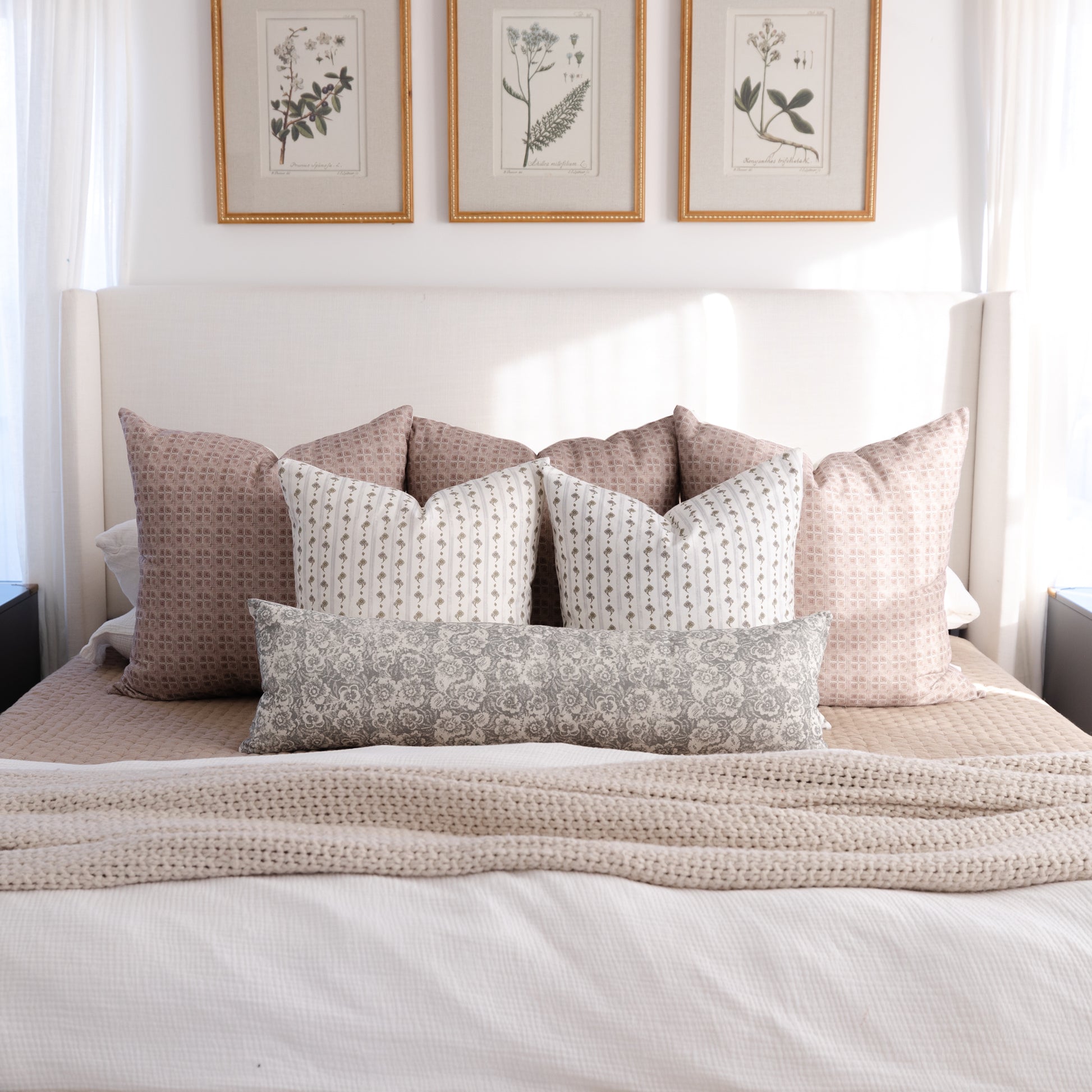 Gray and tan patterned lumbar pillow displayed on a bed with coordinating decorative pillows.