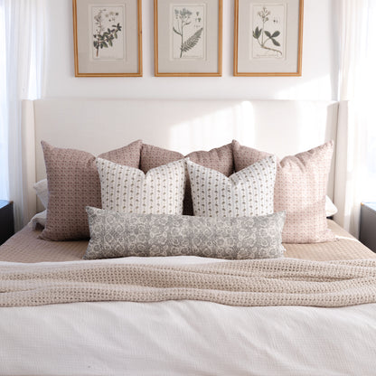 Gray and tan patterned lumbar pillow displayed on a bed with coordinating decorative pillows.