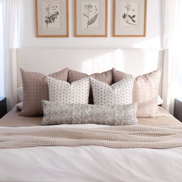 Gray and tan patterned lumbar pillow displayed on a bed with coordinating decorative pillows.
