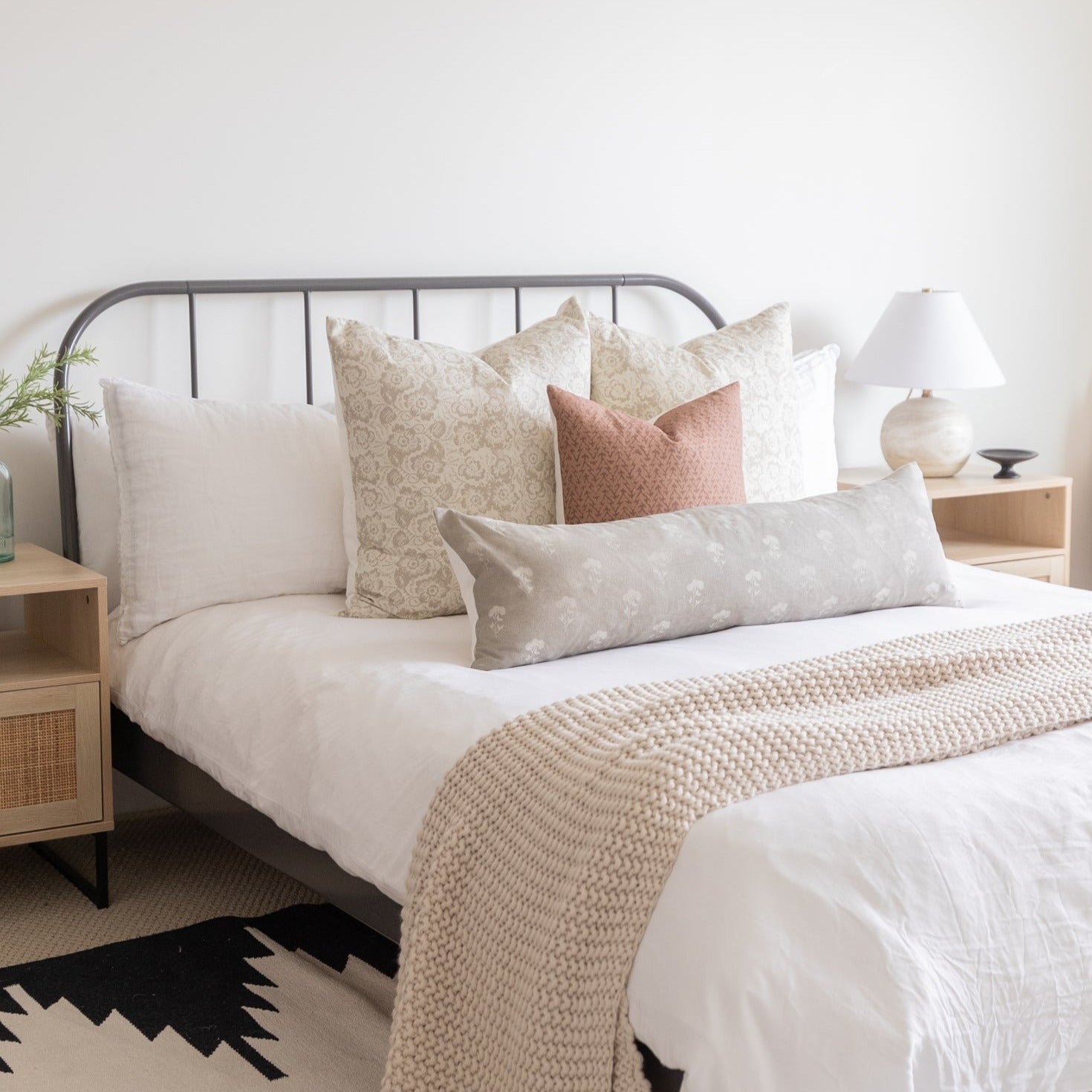 Decorative pillow covers in cream, beige, and mauve tones displayed on a bed with various patterns and textures.