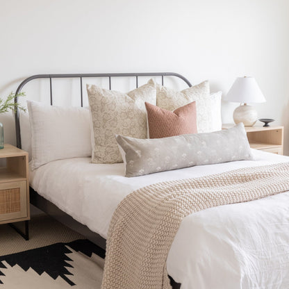 Decorative pillow covers in cream, beige, and mauve tones displayed on a bed with various patterns and textures.