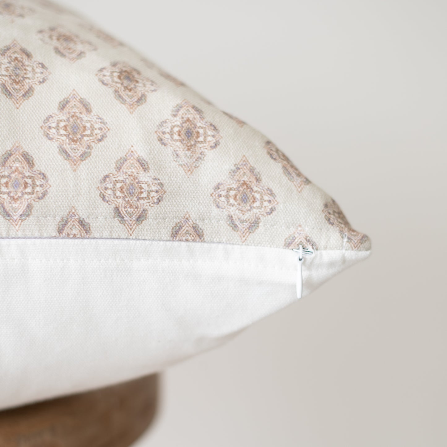 Rectangular pillow with beige and cream geometric diamond pattern and white underside, shown at an angle.