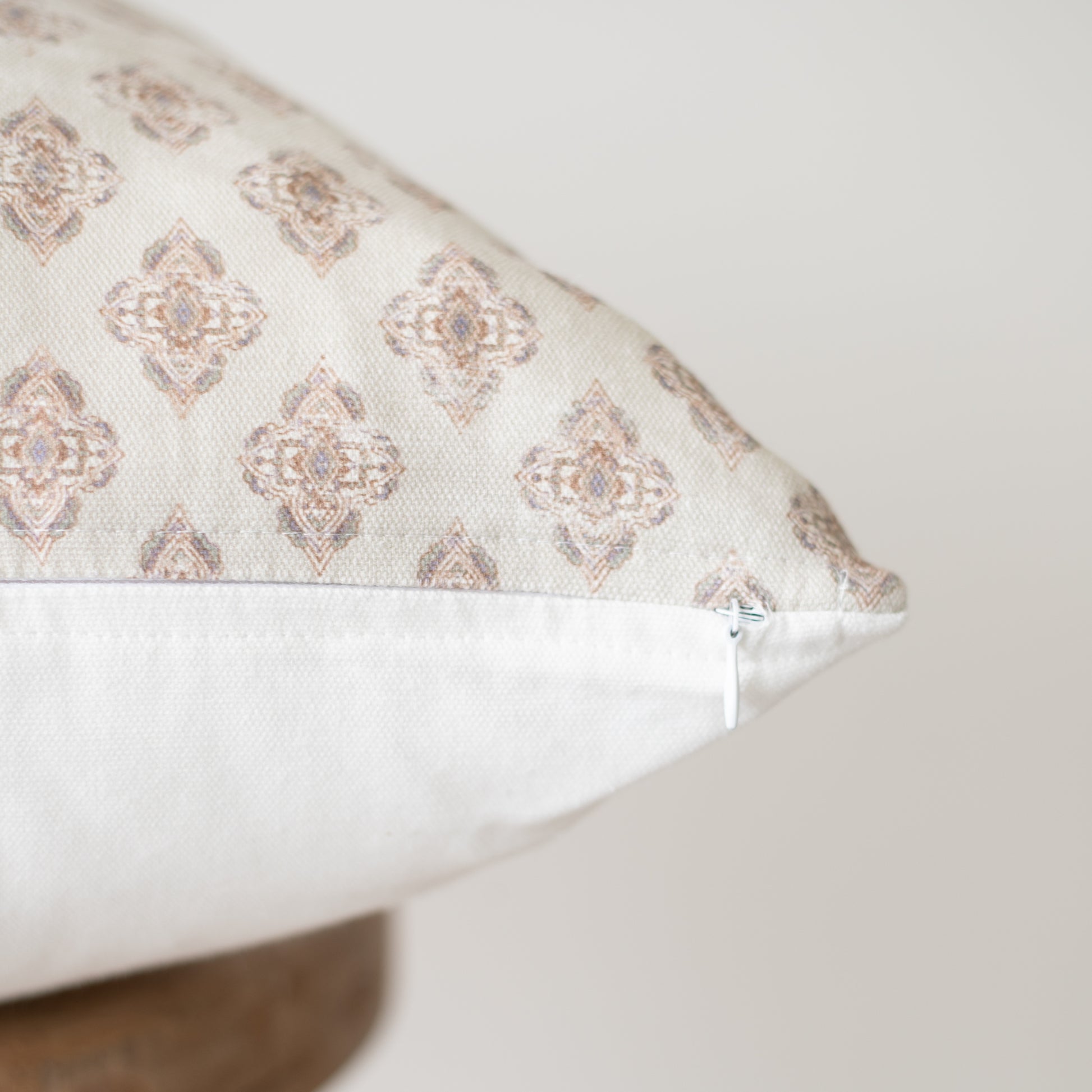 Rectangular pillow with beige and cream geometric diamond pattern and white underside, shown at an angle.