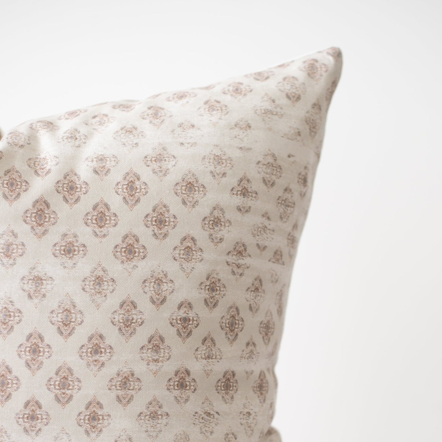 Cream pillow with tan diamond-shaped damask pattern throughout fabric surface.