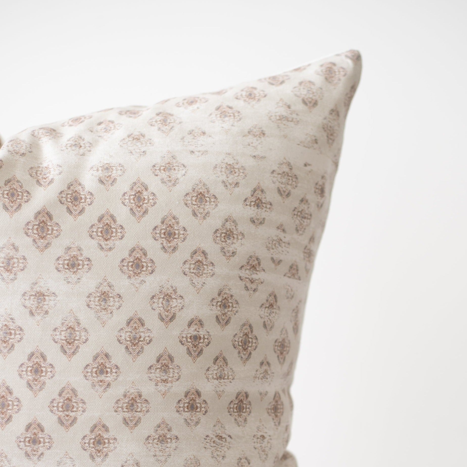 Cream pillow with tan diamond-shaped damask pattern throughout fabric surface.
