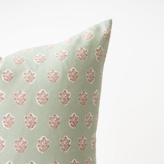 Light green pillow with repeating rose print in dusty pink throughout.