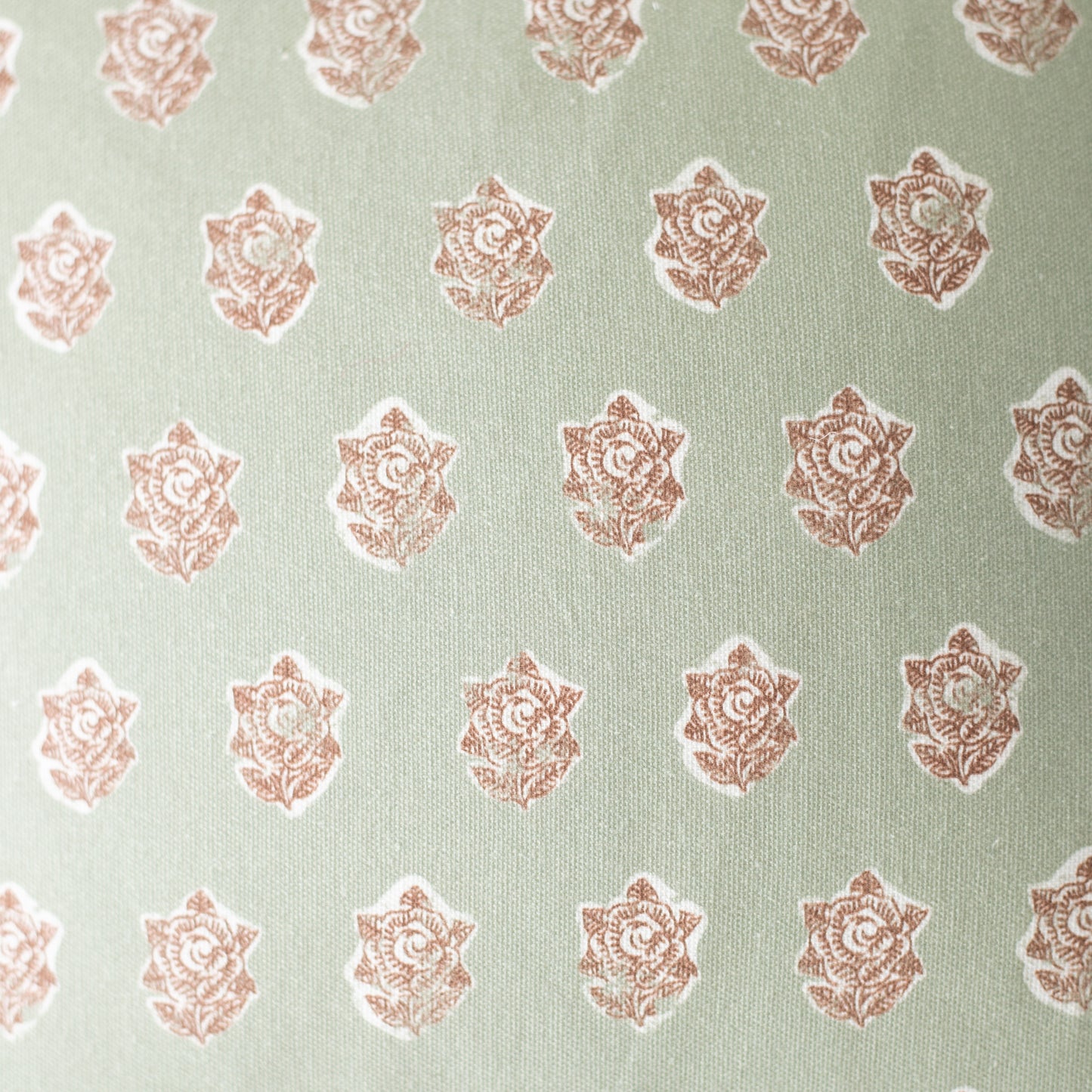 Sage green fabric with repeating rose-colored ornamental floral medallion pattern.