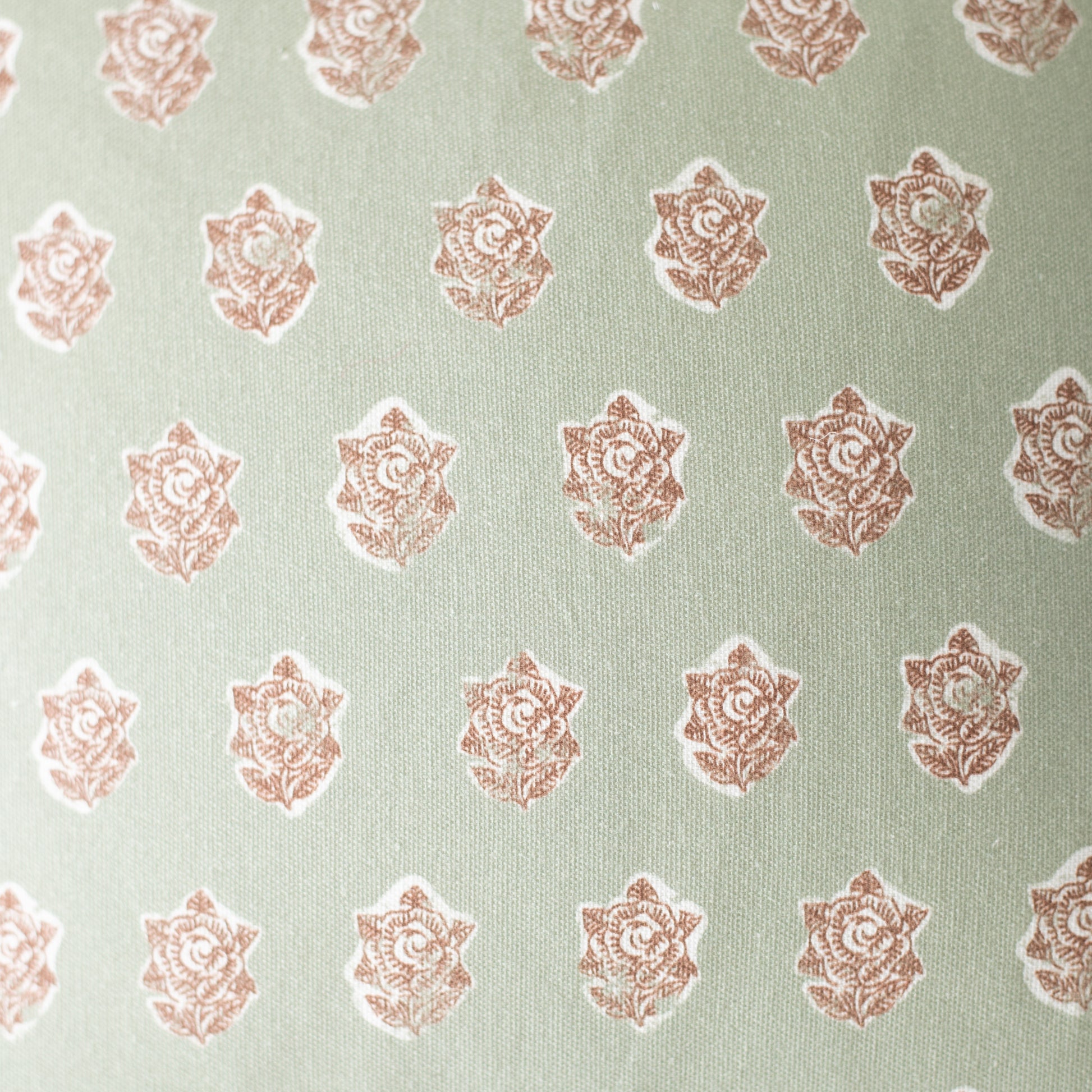 Sage green fabric with repeating rose-colored ornamental floral medallion pattern.