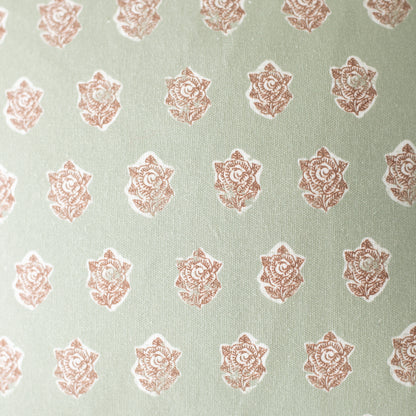 Sage green fabric with repeating rose-colored ornamental floral medallion pattern.