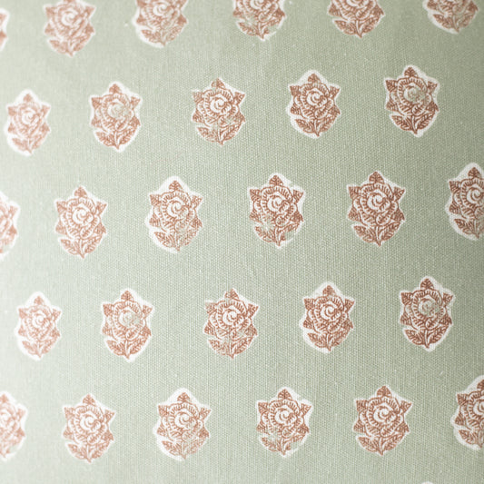 Sage green fabric with repeating rose-colored ornamental floral medallion pattern.