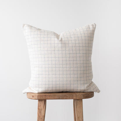 Cream pillow cover with gray grid pattern displayed on wooden stool.