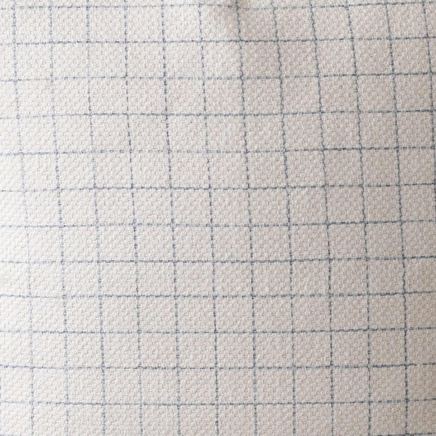 Light beige quilted fabric with gray grid pattern lines, textured surface.