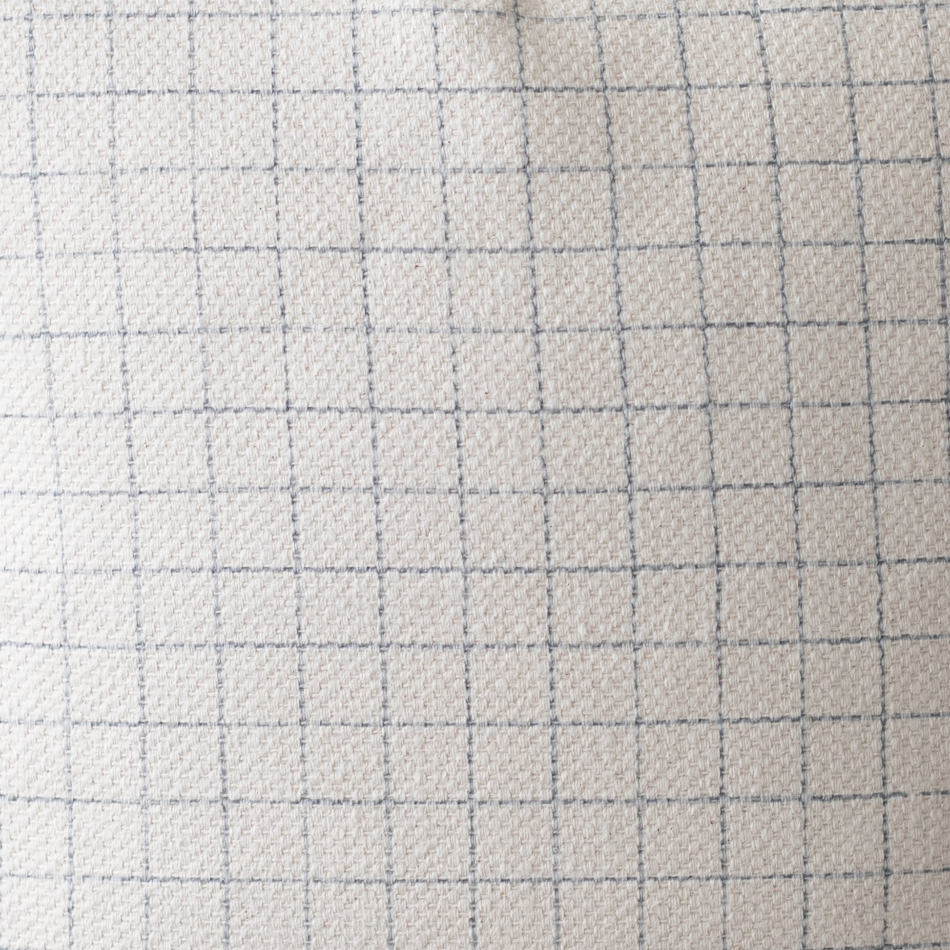 Light beige quilted fabric with gray grid pattern lines, textured surface.