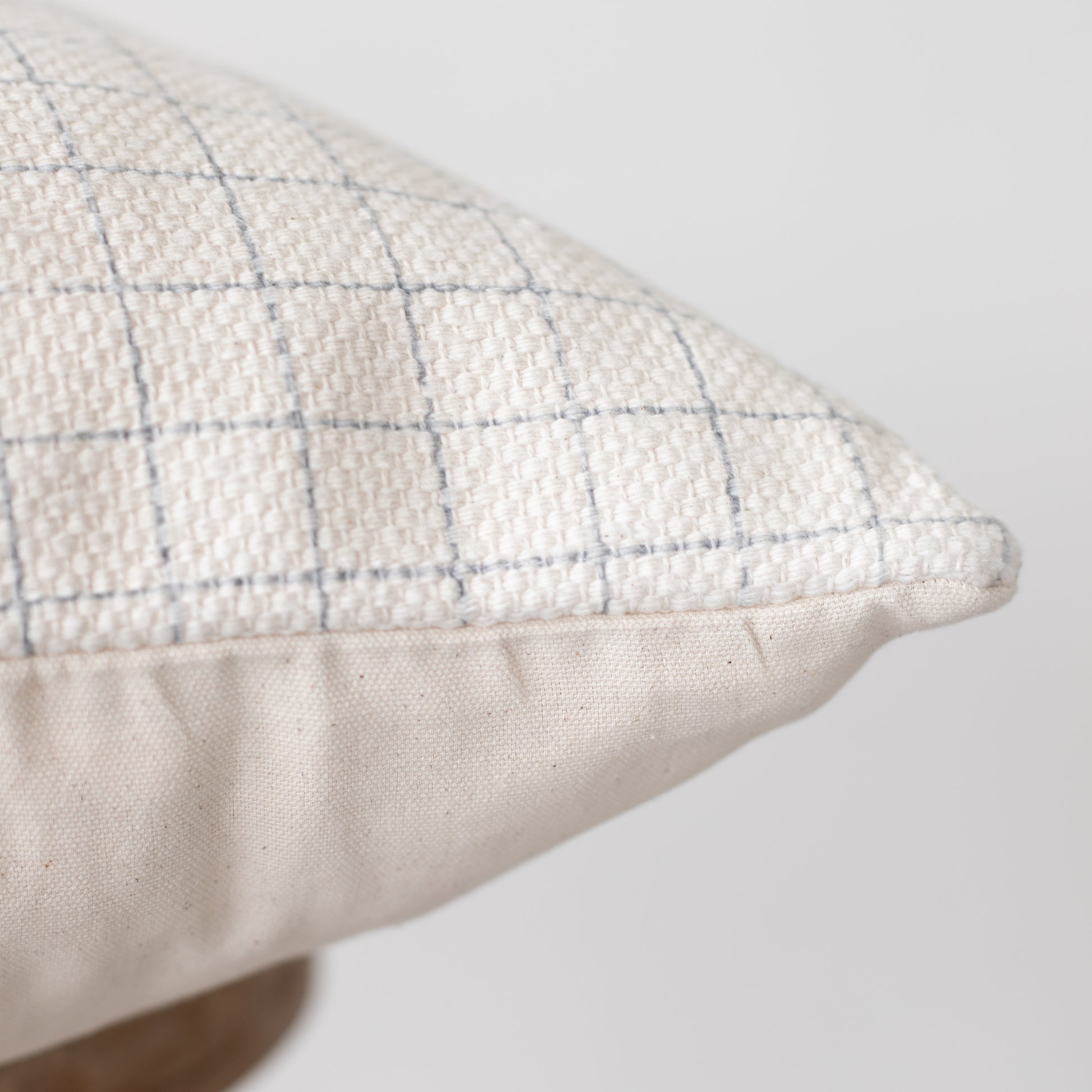 Cream-colored pillow with blue grid pattern and solid cream underside.