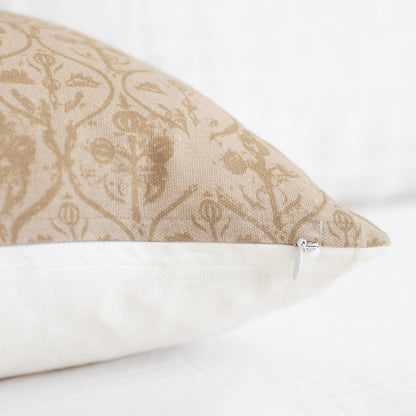 Rectangular pillow with tan floral hourglass pattern on upper half and cream solid fabric on lower half, with zipper closure.