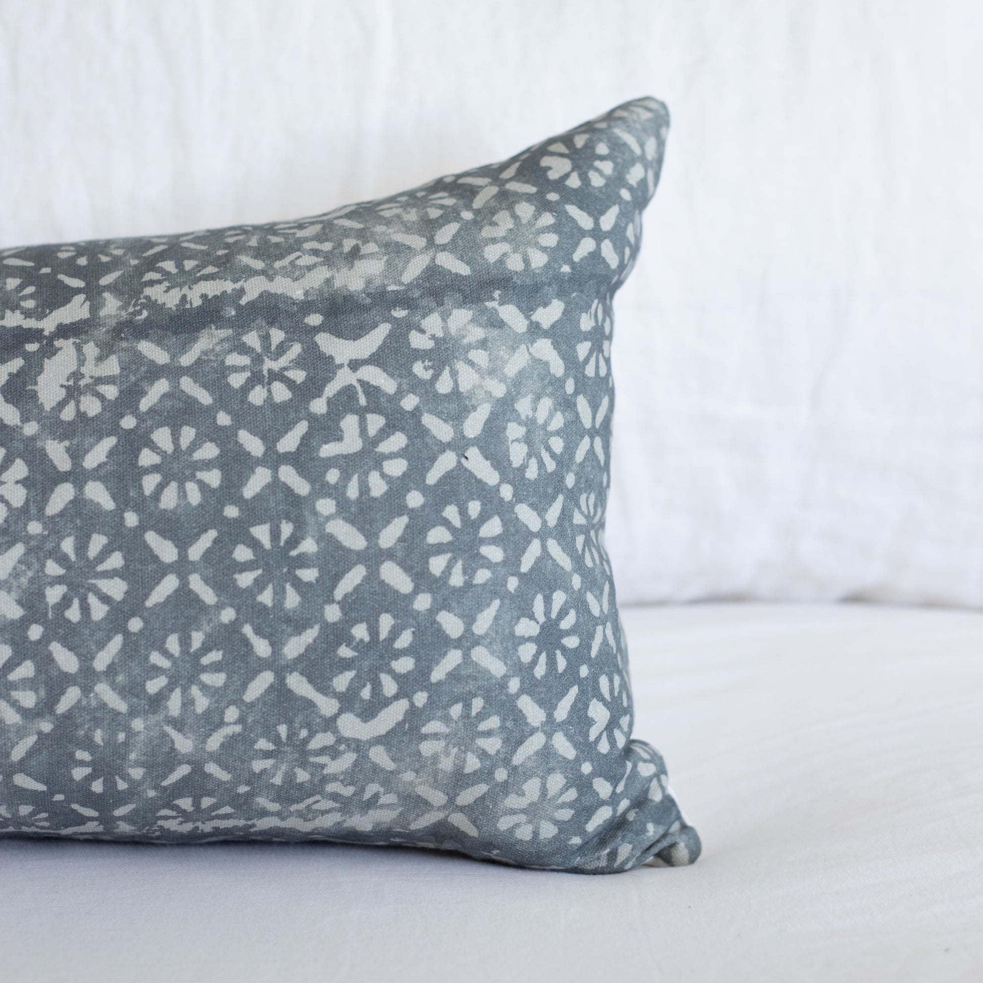 Gray lumbar pillow with cream diamond and floral geometric pattern on white background.