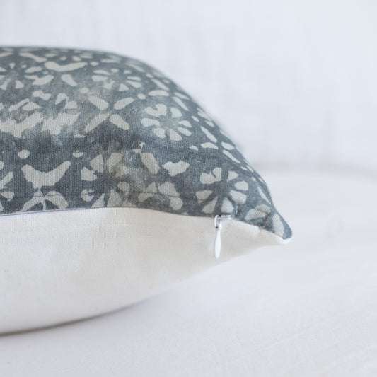 Rectangular pillow with gray and white floral diamond pattern, white zipper closure visible on side.