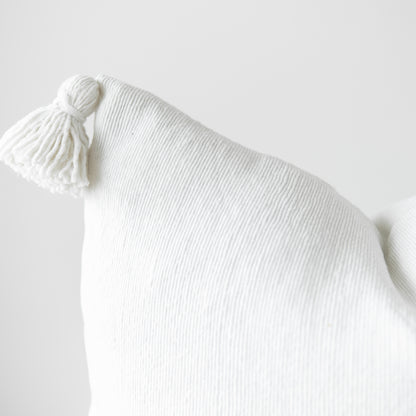 White ribbed throw pillow with corner tassel detail, 22 inches.