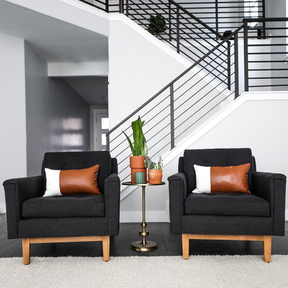 Two cognac leather lumbar pillows displayed on black armchairs in a modern living room setting.
