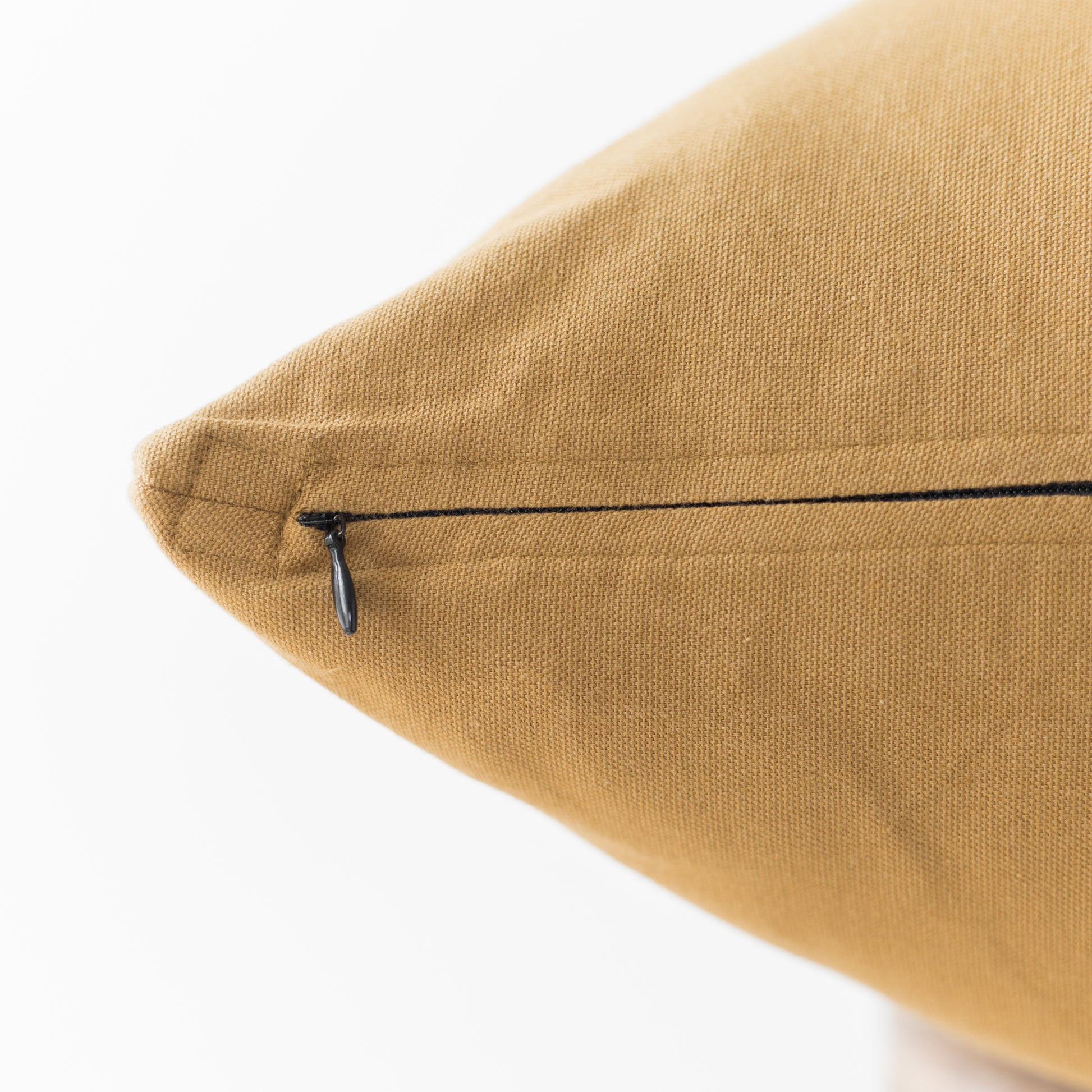 Golden tan woven pillow cover with black zip closure on seam.