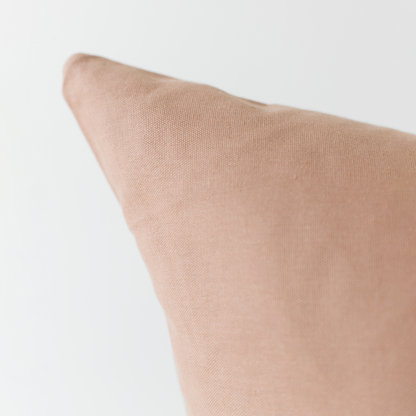 Dusty rose solid-colored pillow with textured fabric surface and angled corner detail.
