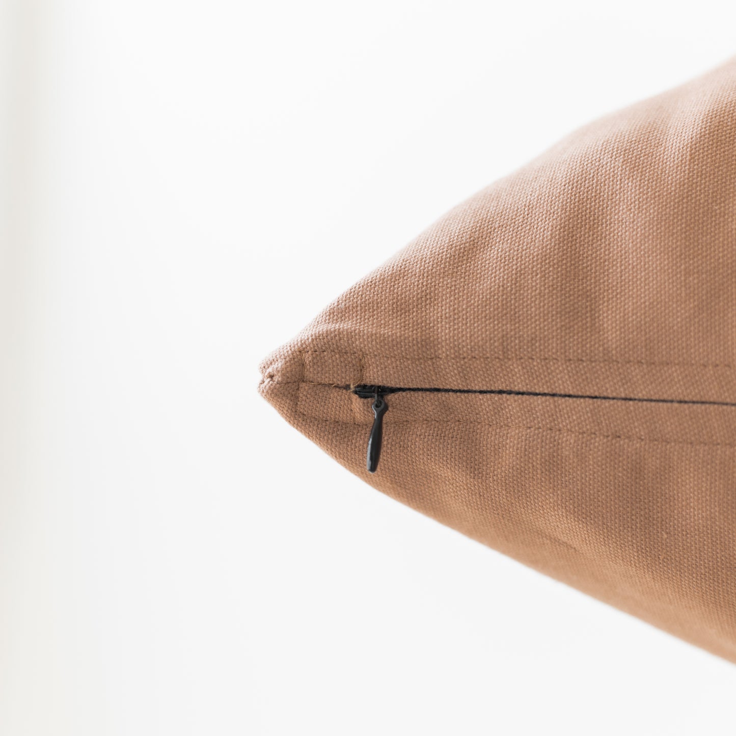 Dusty rose pillow with textured linen fabric and black zipper closure detail.