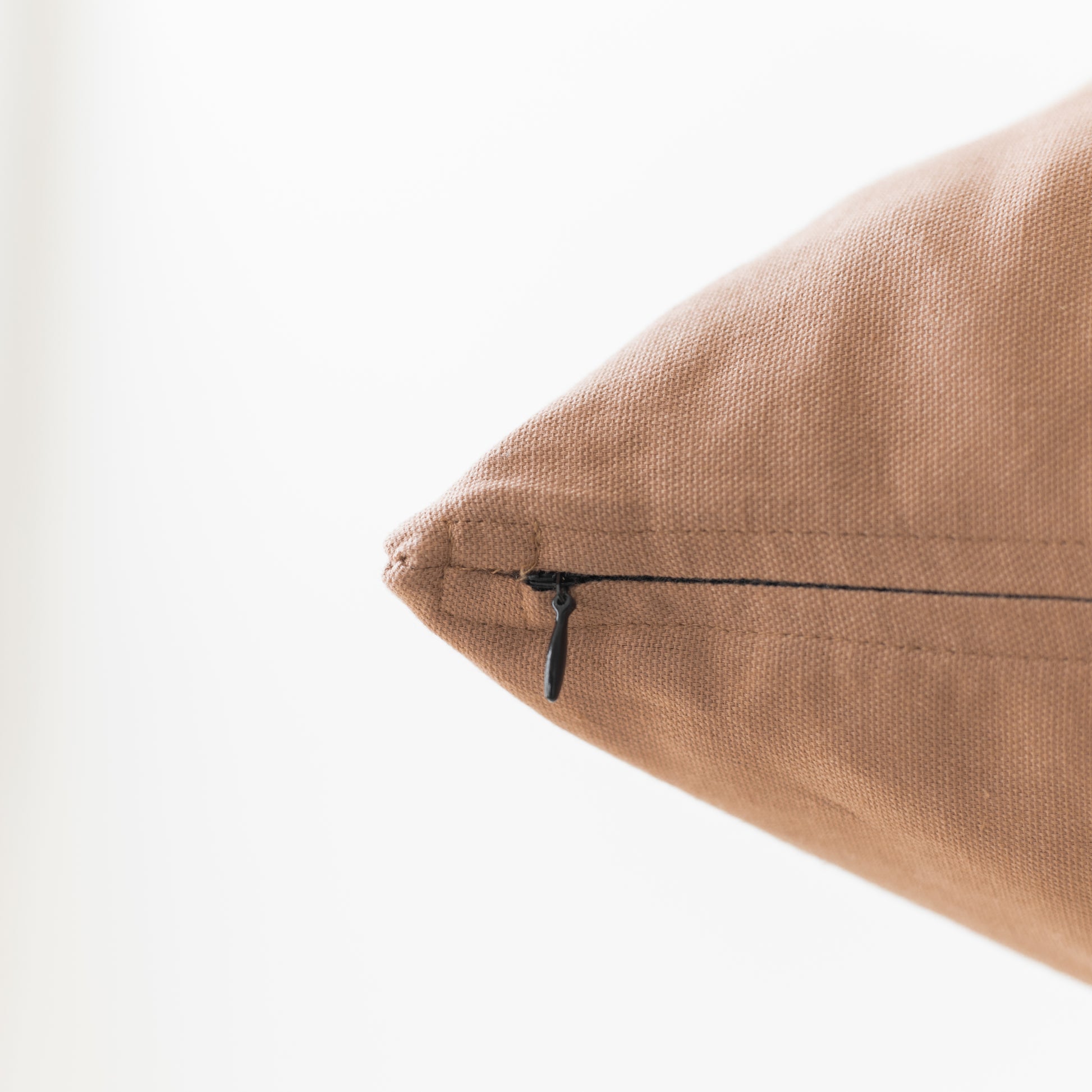 Dusty rose pillow with textured linen fabric and black zipper closure detail.