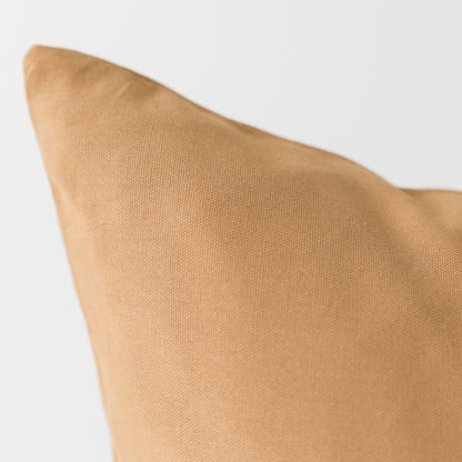 Terracotta-colored pillow with textured woven fabric and angled corner visible against white background.