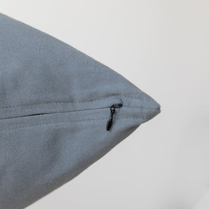 Blue-gray textured pillow with black zipper closure on seam.