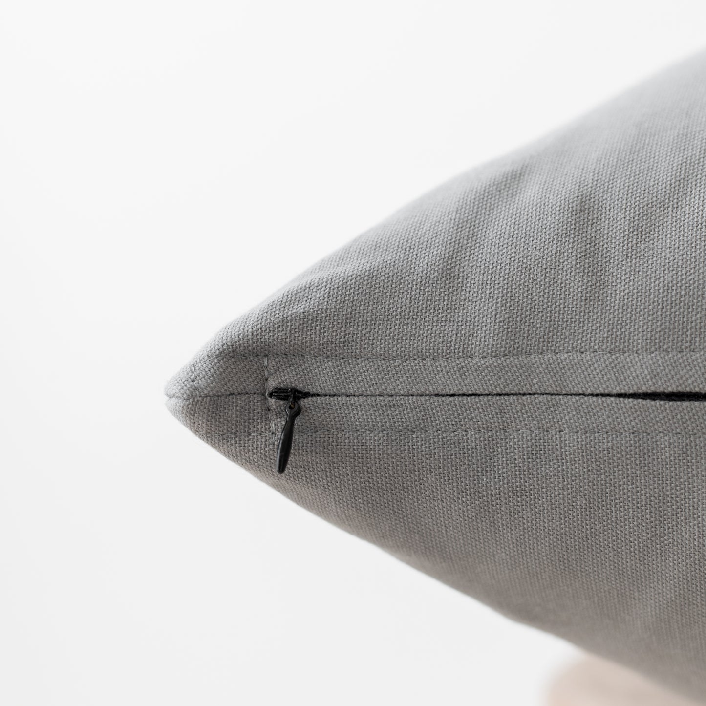 Gray textured pillow with concealed zipper closure, close-up detail view.