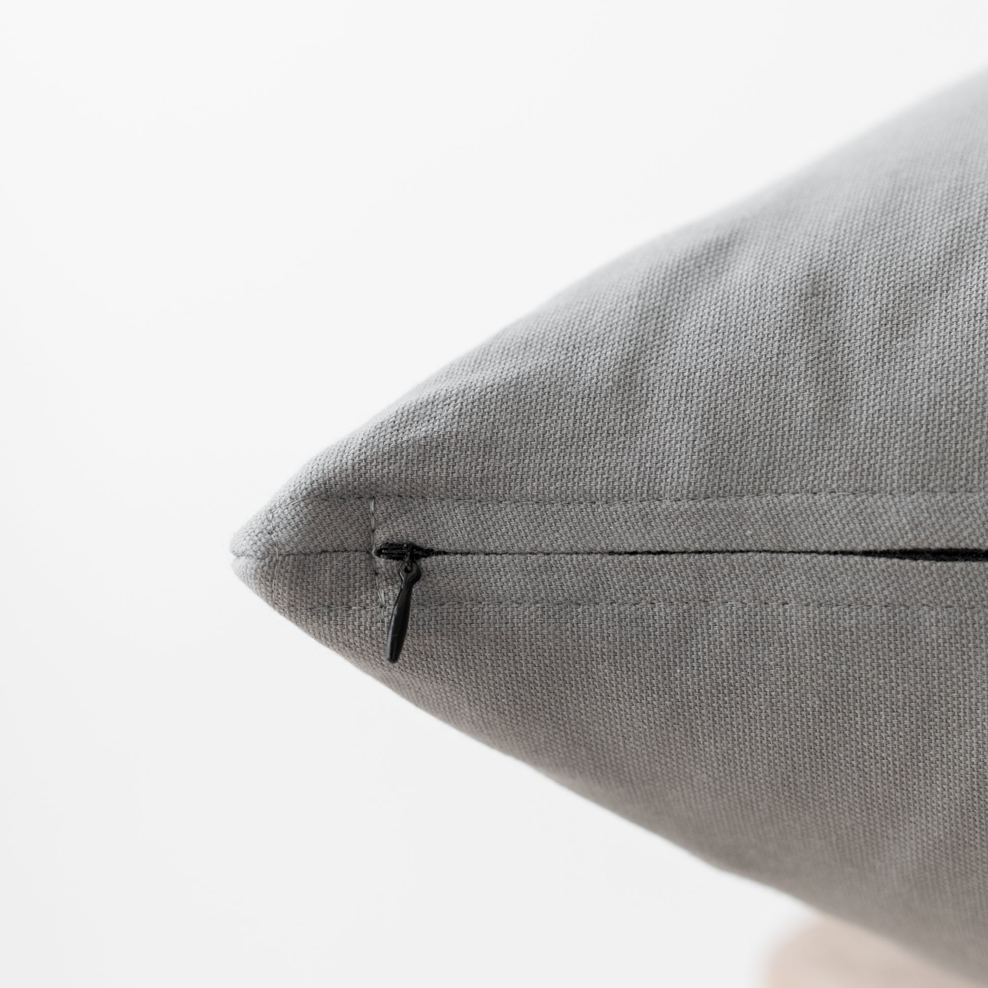 Gray textured pillow with concealed zipper closure, close-up detail view.